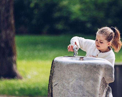 Erfrischung gefällig? Mädchen trinkt von Trinkbrunnen