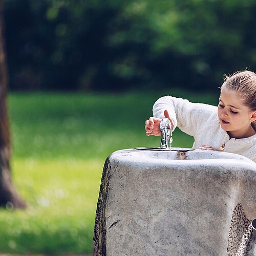 Mädchen trinkt von Trinkbrunnen