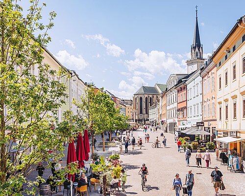 Menschen schlendern über den Hauptplatz Villach Belebtes Stadtzentrum von Villach