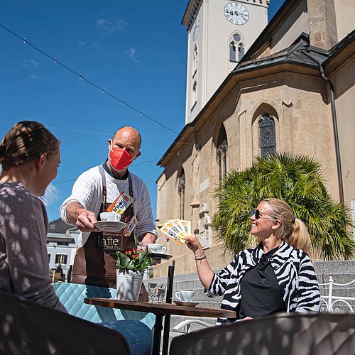 Friends are paying their coffee in Villach's downtown with the LOKAL BONUS vouchers