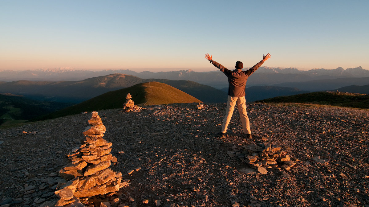 Man reaching for the sky on the mountain summit 