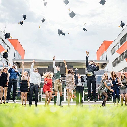 Studierende schmeißen Absolventenhut in die Luft