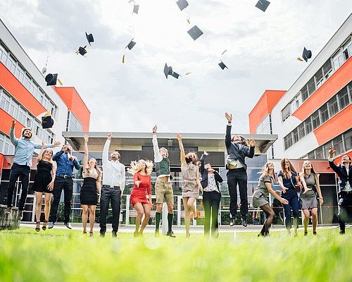 Studierende schmeißen Absolventenhut in die Luft