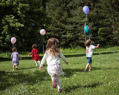 Kinder spielen mit Luftballons