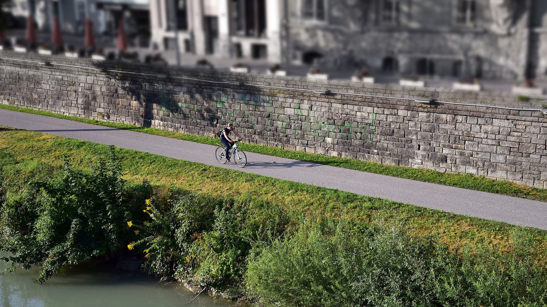 Radfahrerin fährt dem Drauufer entlang