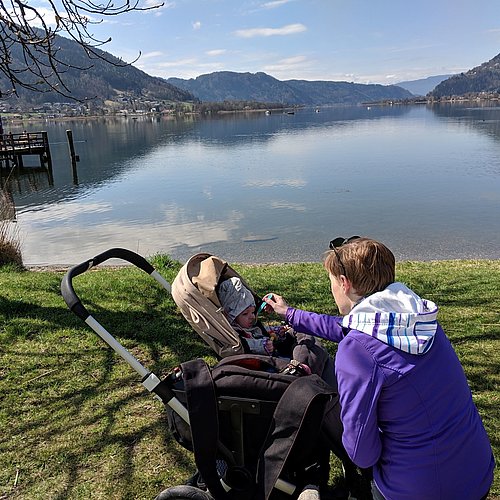 Mutter füttert Kind im Kinderwagen in Villach