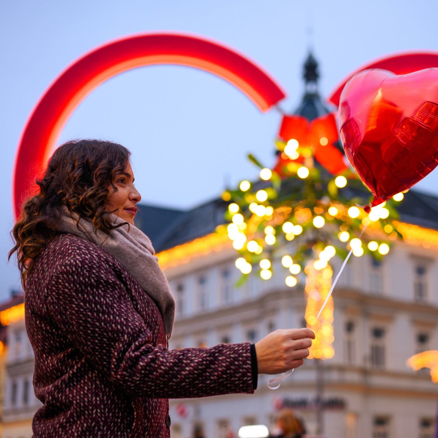 Frau mit Herzluftballon vor einem Herzrahmen