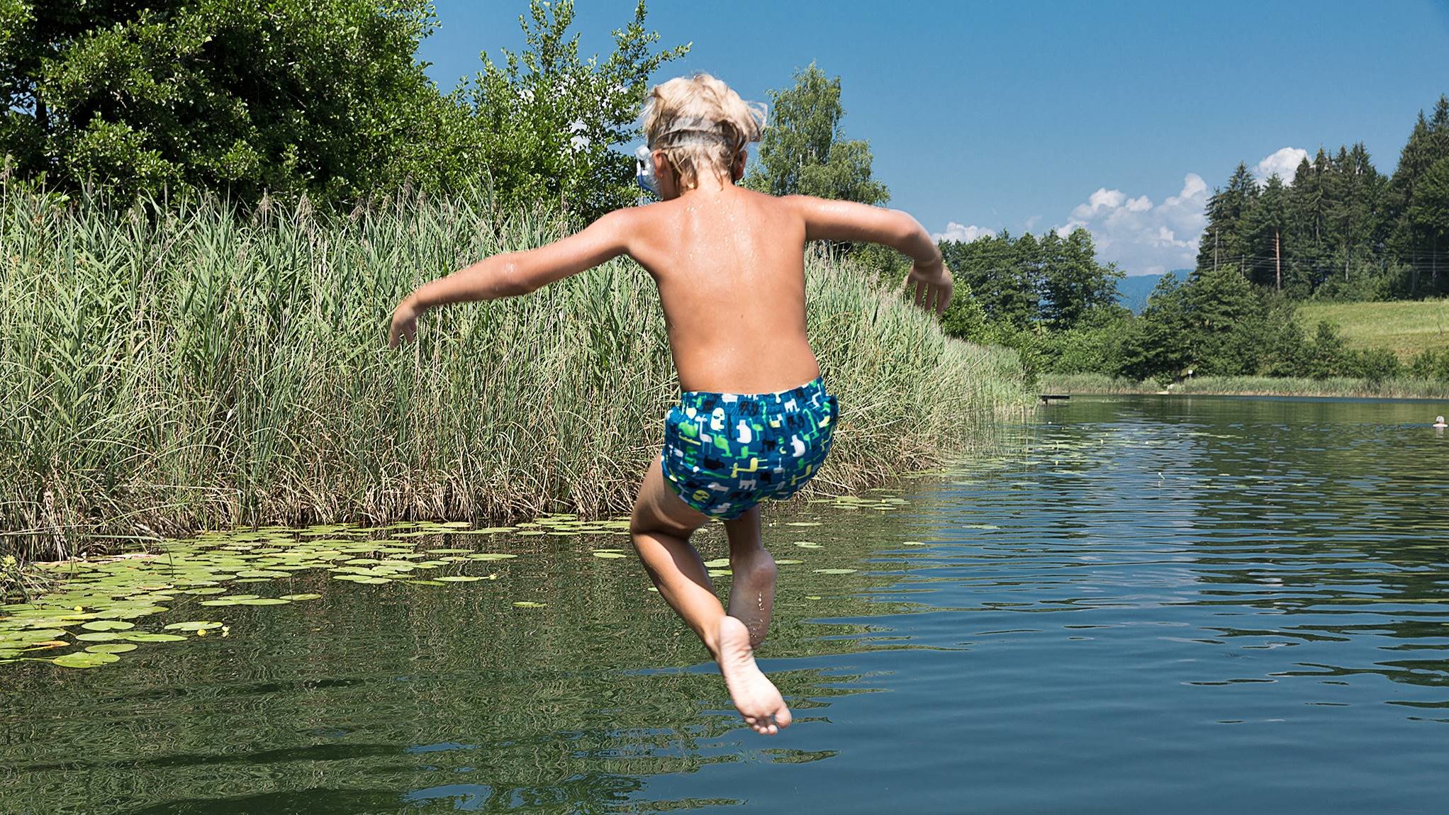 Child jumps into the refreshing water of Lake Aichwaldsee