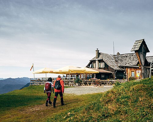 Zwei Personen vor einer Hütte am Berg