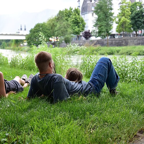 Familie liegt in einer Wiese des Drauufers