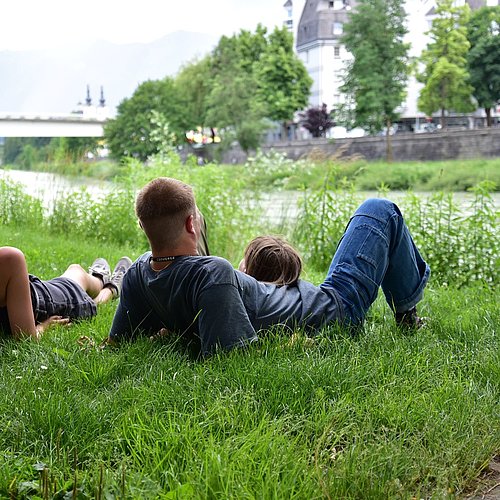 Family lying on the gras near the riverside of Drau