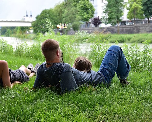 Family lying on the gras near the riverside of Drau