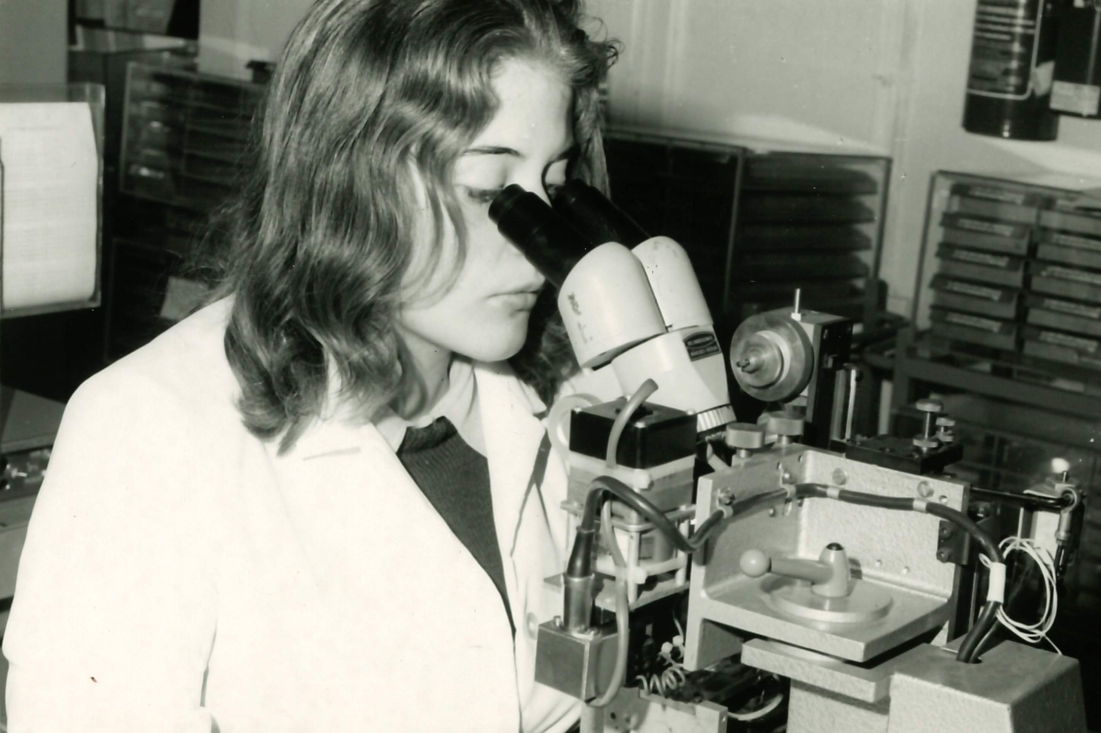 Forscherin der Diodenproduktion blickt durch ein Microskop