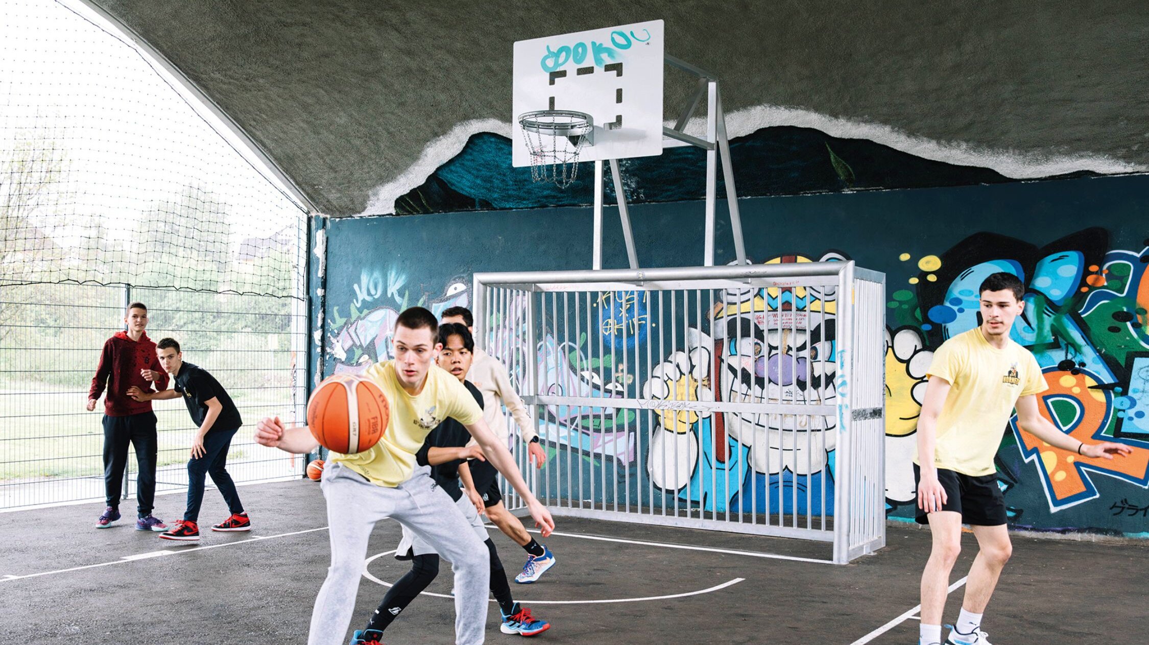 Young people playing basketball under the war bridge in Villach