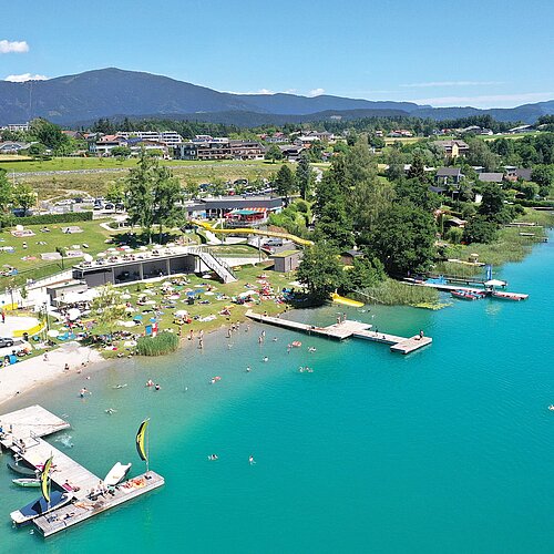 A bird's eye view of turquoise-blue Lake Faak with the Drobollach lido