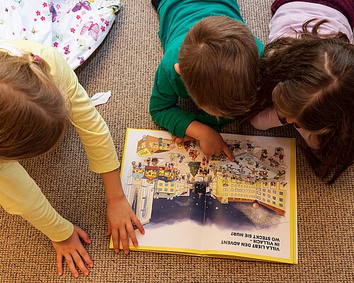 Kinder schauen sich ein Bilderbuch an