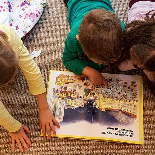 Kinder schauen sich ein Bilderbuch an