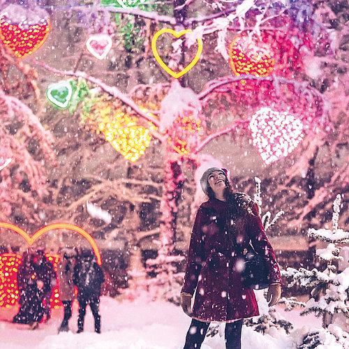 Besucherin betrachtet die Lichter des Winter Wunder Walds in Villach