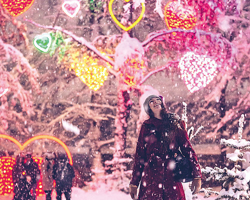 Besucherin betrachtet die Lichter des Winter Wunder Walds in Villach