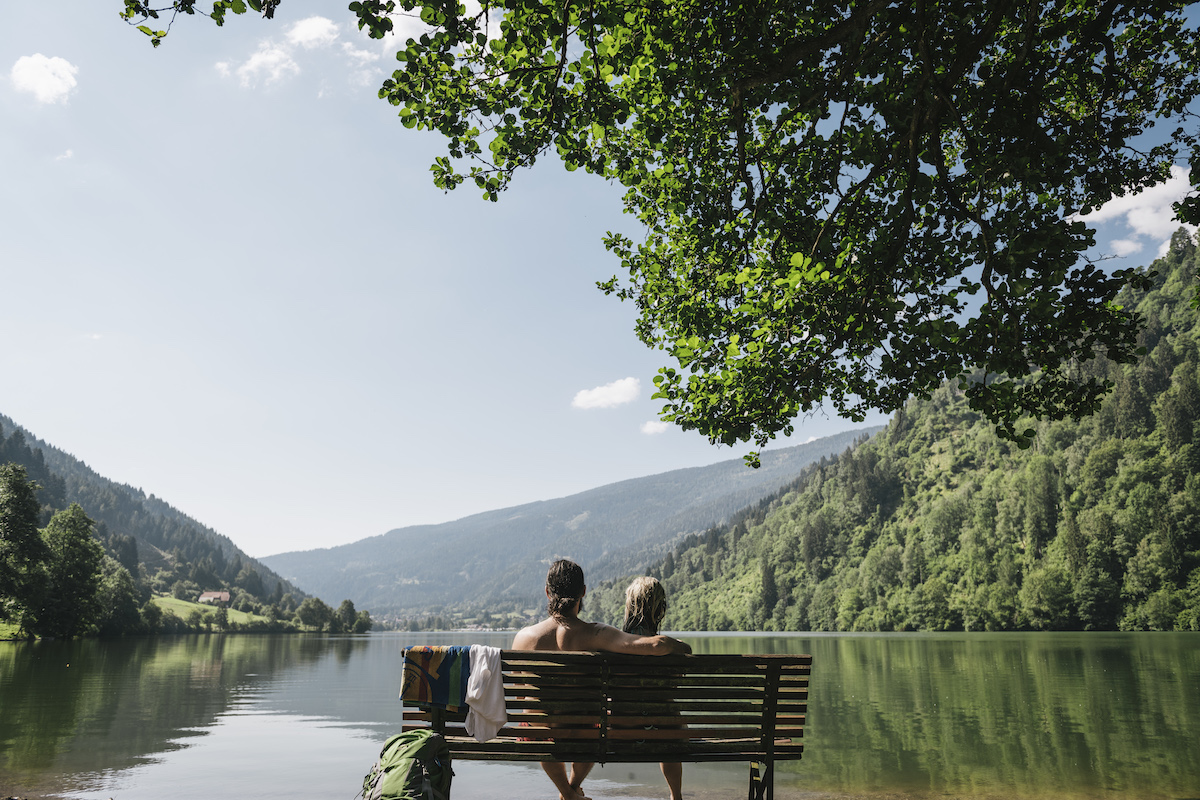 Couple sitting on a bench facing lake Affritzer See