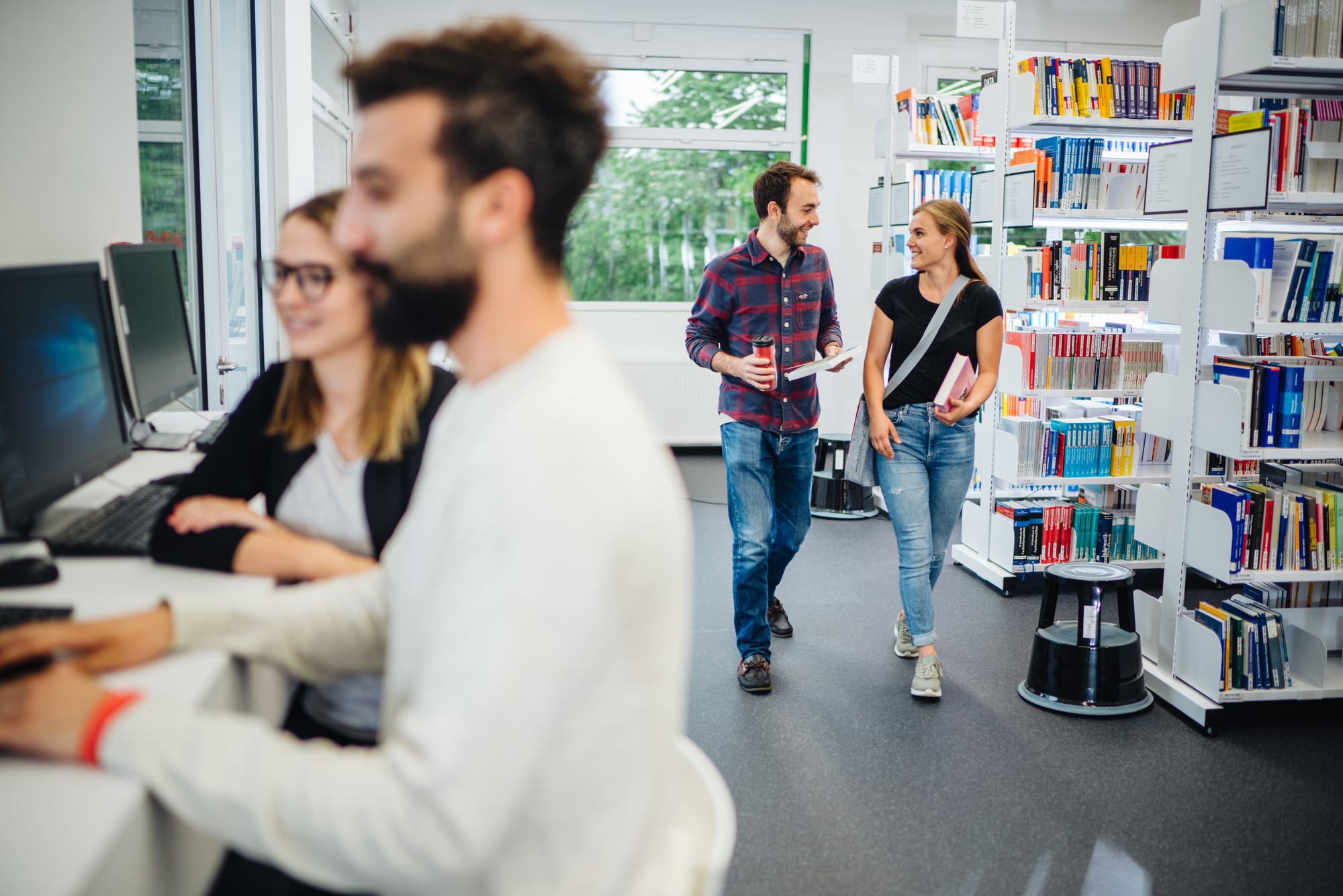 Students carrying books in a library