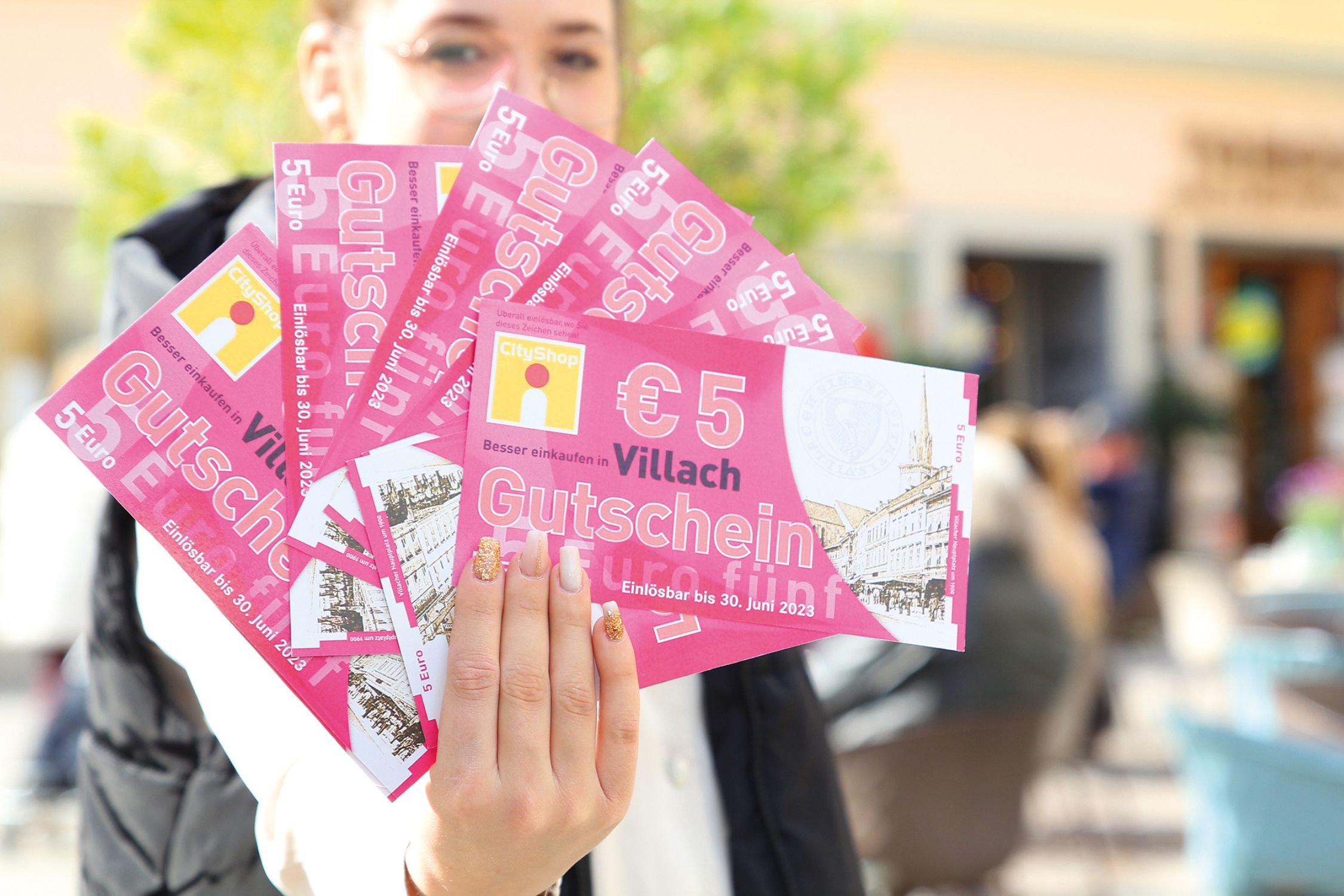 A woman holds up the coupons in front of her face