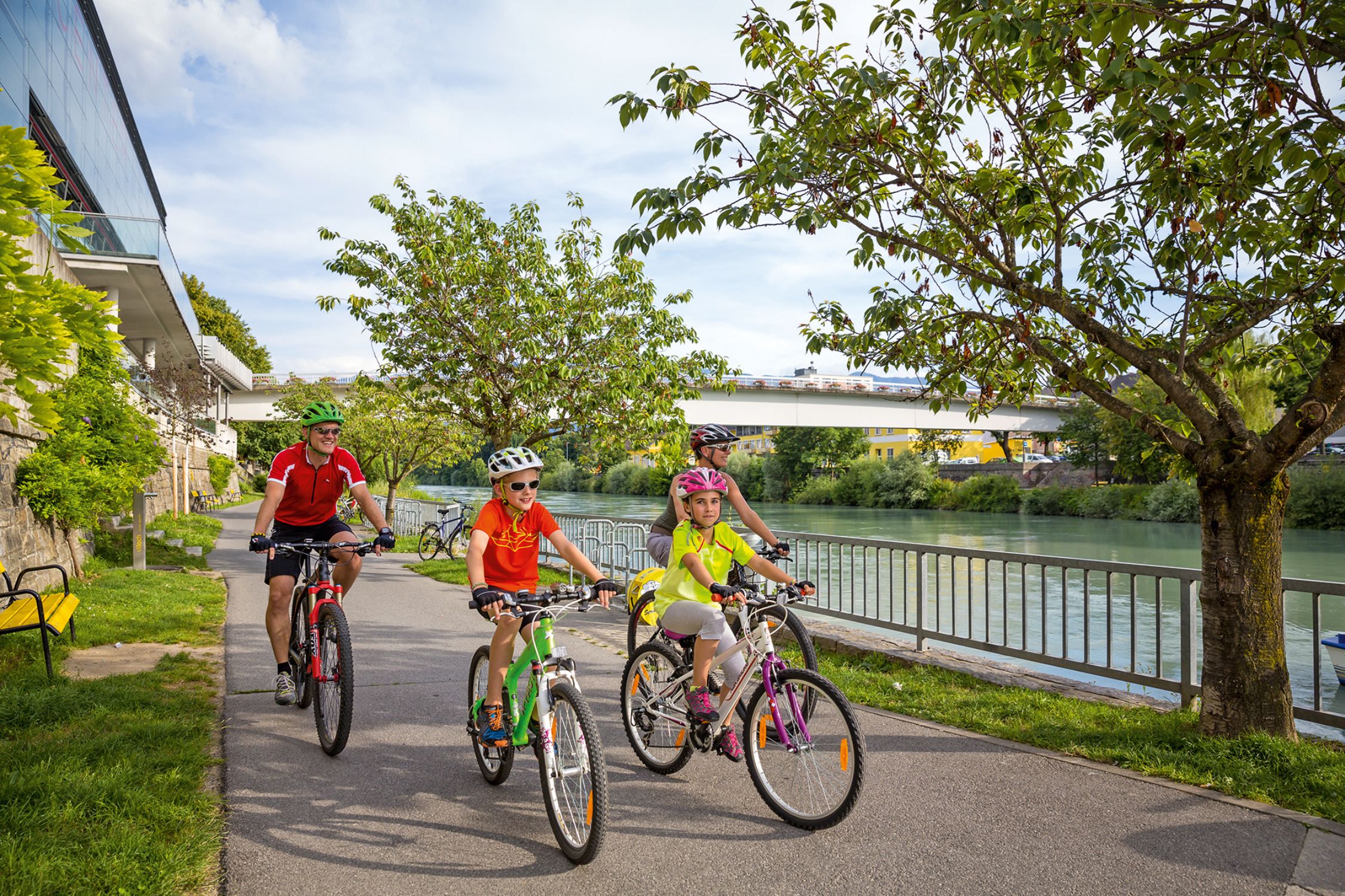 Family riding the bike along the Drau river