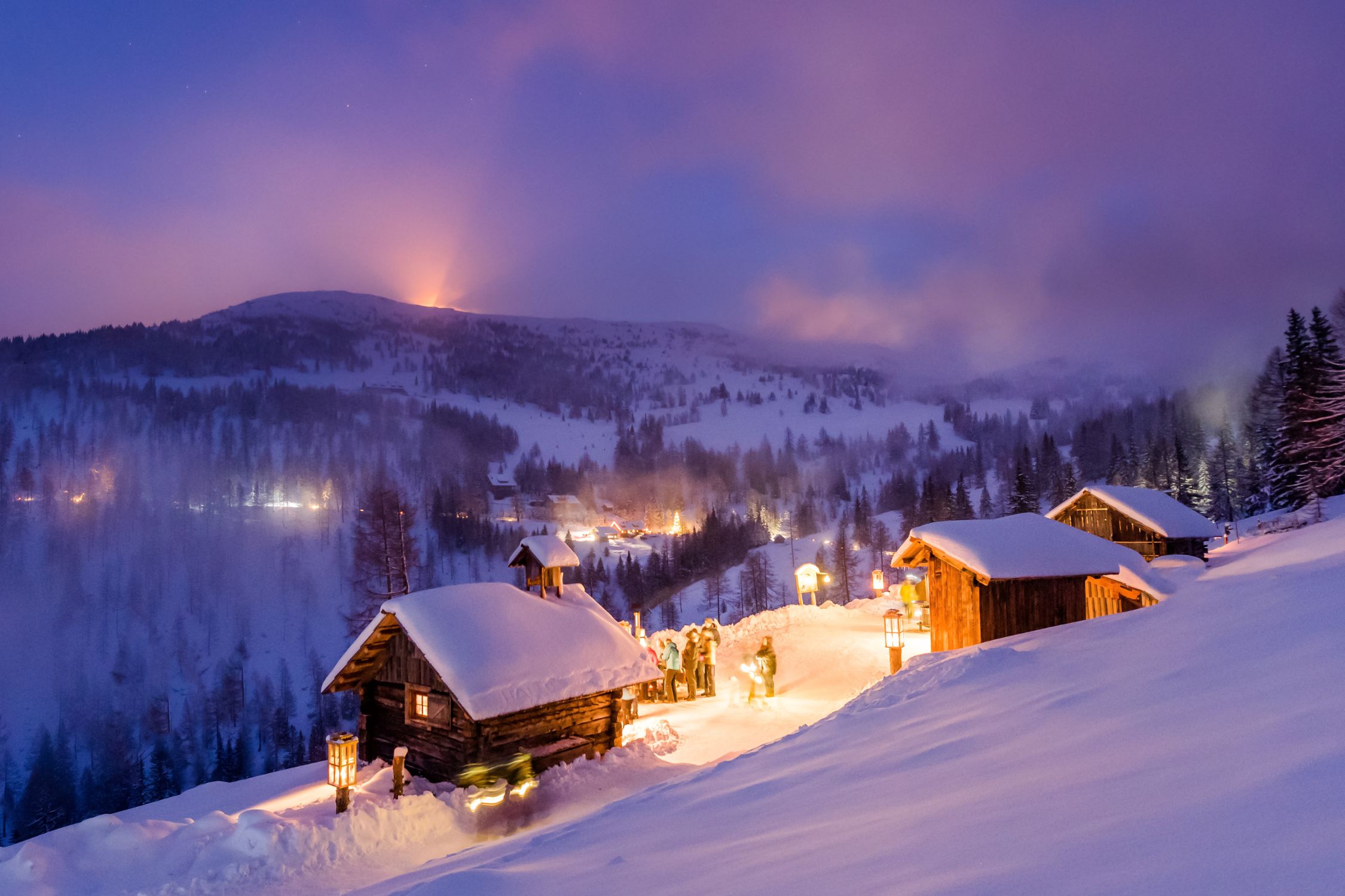 Beleuchtete Hütte in den verschneiten Bergen