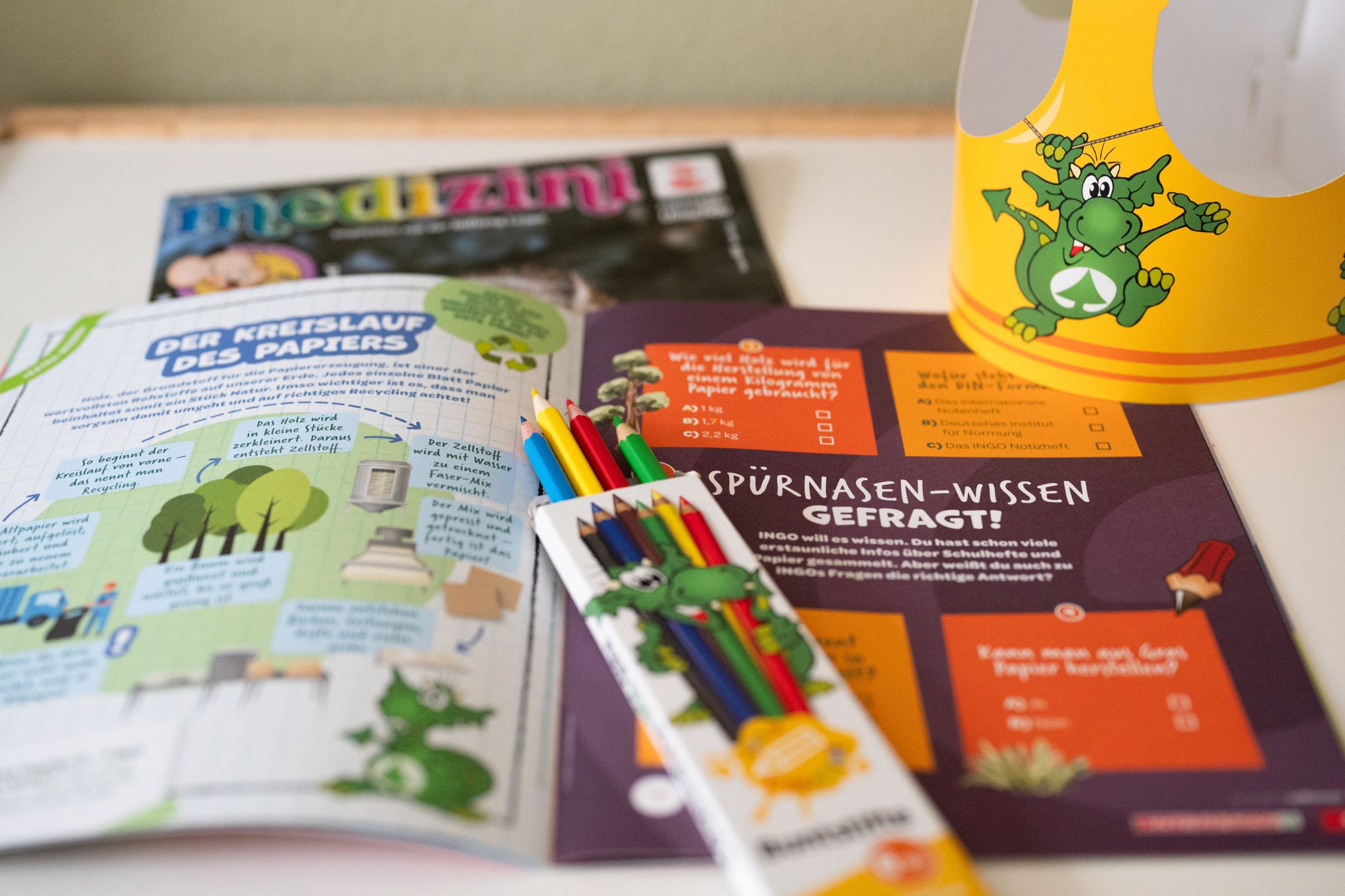 Aufgeschlagene Kinderzeitschriften mit Buntstifte und Krone