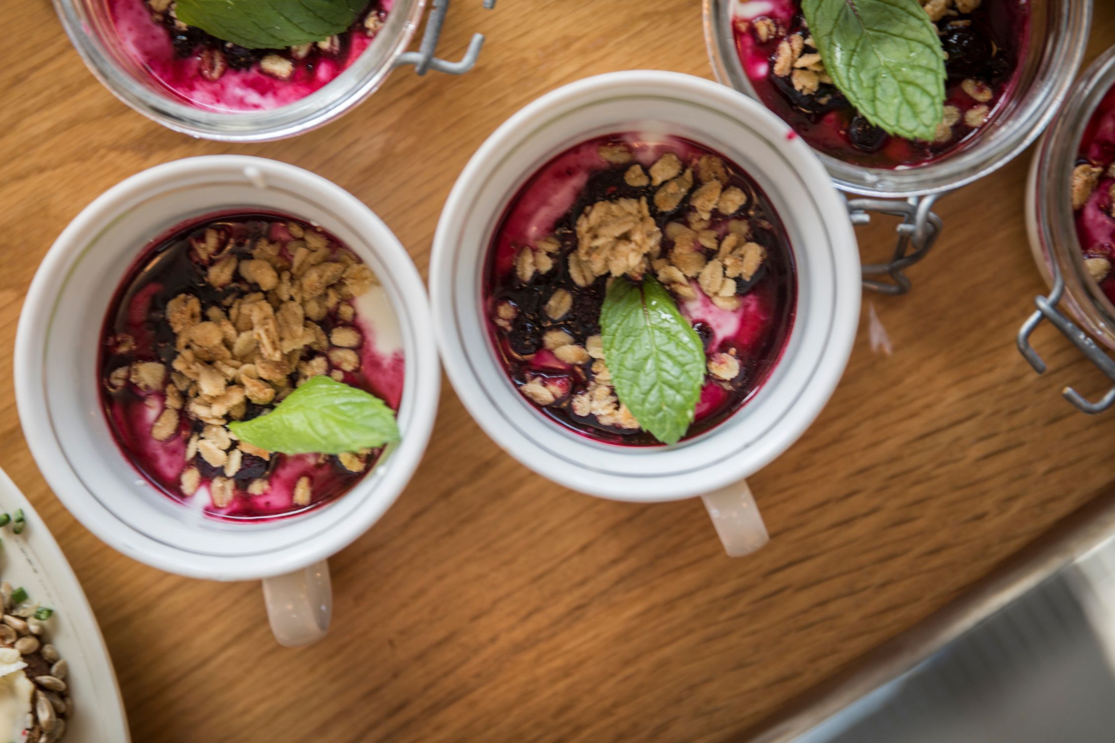 Müsli in Tassen mit Früchten und einem Minzblatt